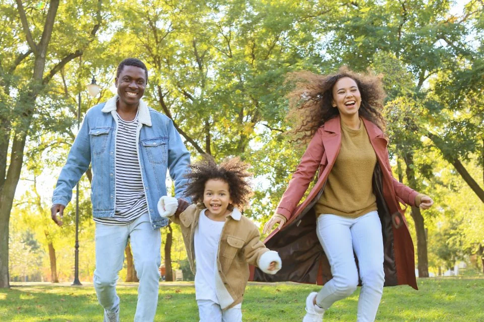 Family running and laughing together in a park