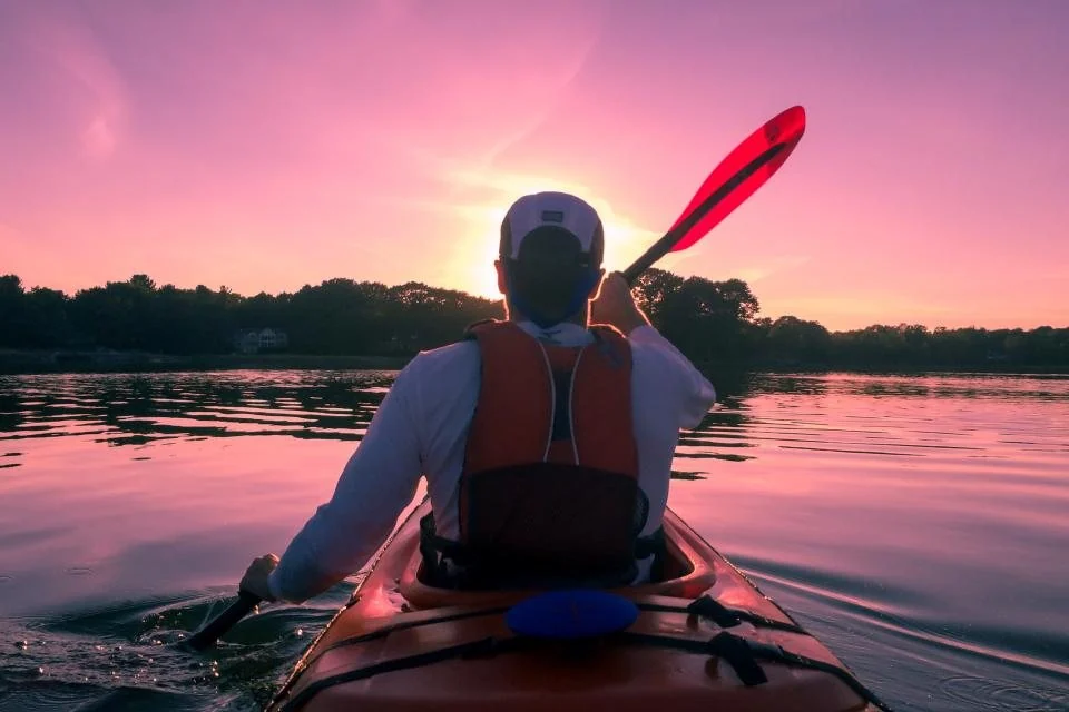 Person kayaking on a lake at sunset