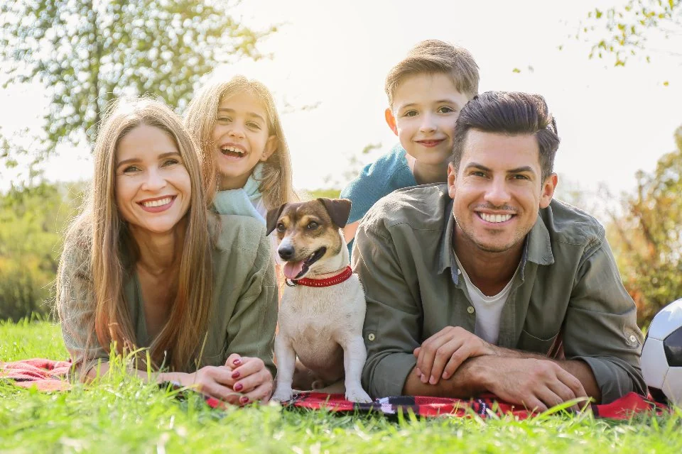 Family lying on the grass with their dog