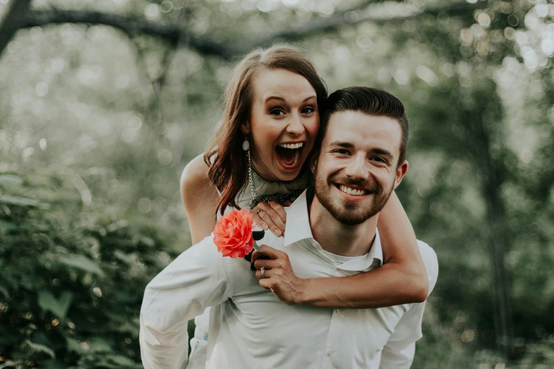 Laughing couple, woman riding piggyback on man outdoors